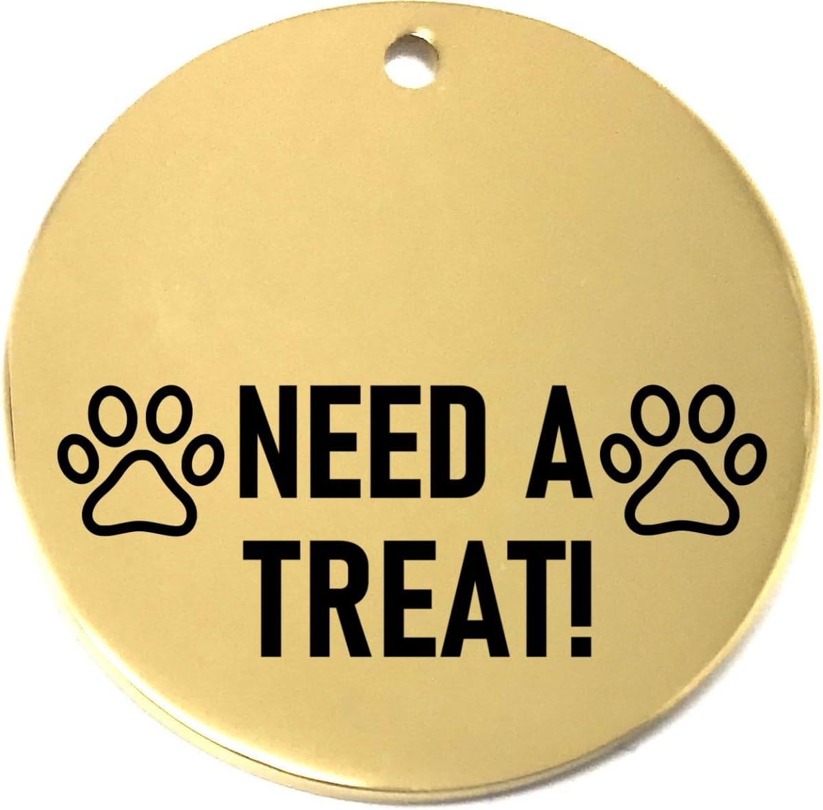 Gold pet tag with 'NEED A TREAT!' text and paw prints on a white background