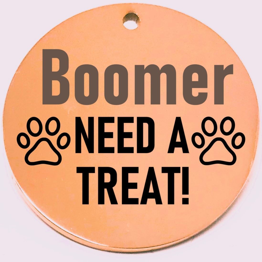 Round rose gold pet id tag with 'Boomer NEED A TREAT!' text and paw prints on a white background