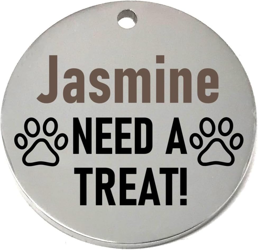 Round silver pet id tag with 'Jasmine NEED A TREAT!' text and paw prints on a white background