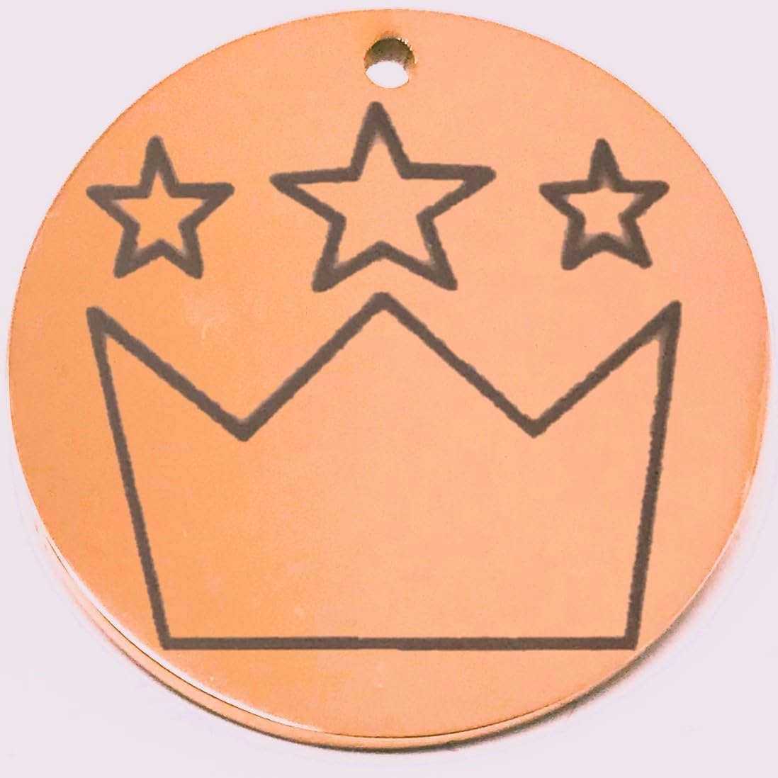 Round peach-colored pet tag with a black crown and star design on a white background