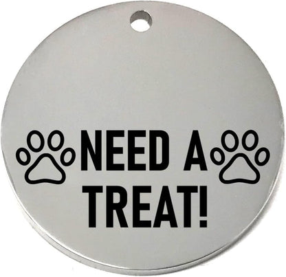 Round silver pet name tag with 'NEED A TREAT!' text and paw prints on a white background